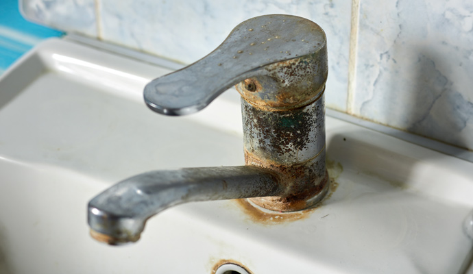 Corroded bathroom faucet showing signs of water damage and rust