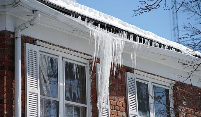 Icicles hanging from a clogged gutter of a house