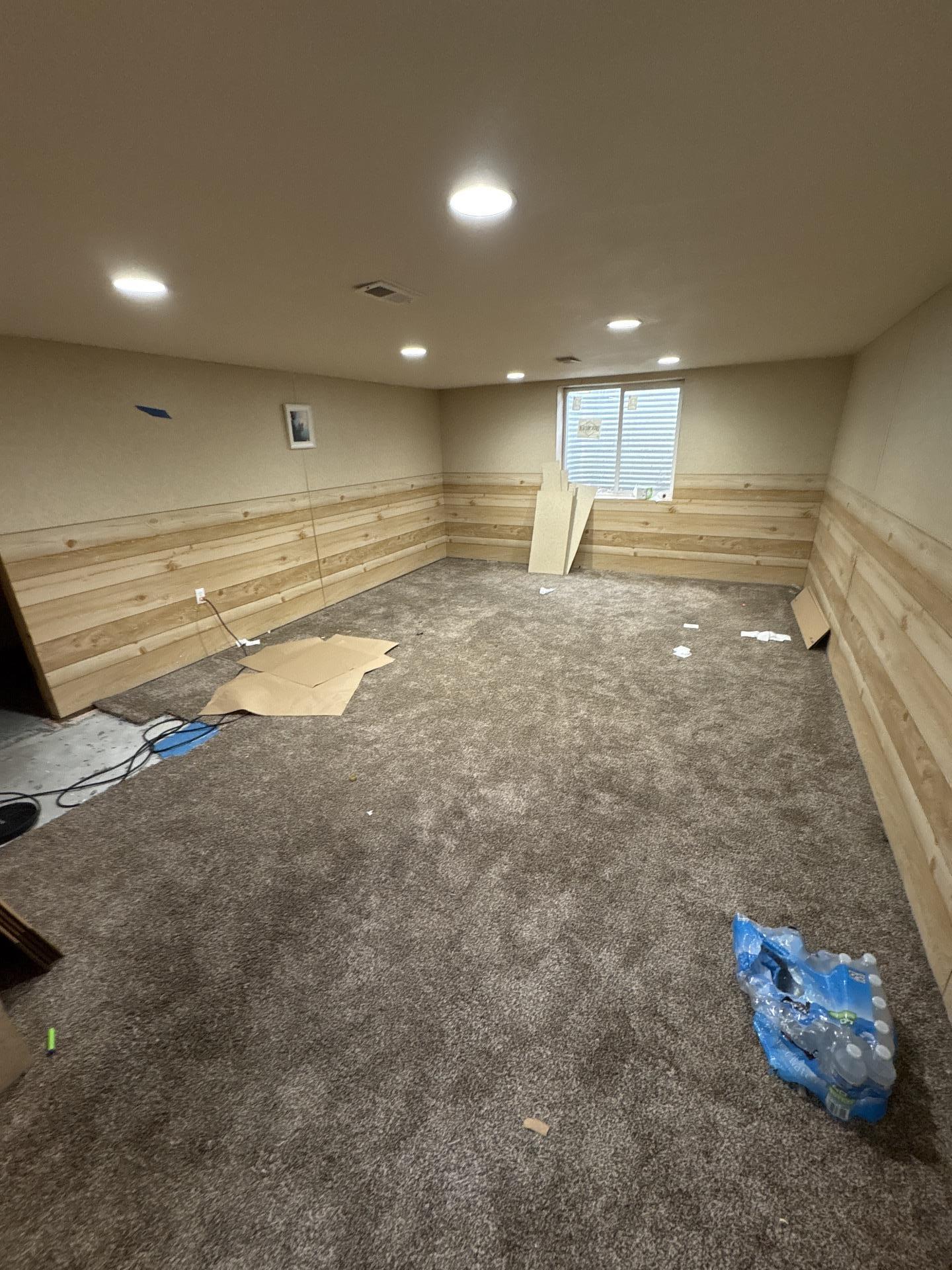 Restored basement room with new wood wainscoting and carpet after water damage repair