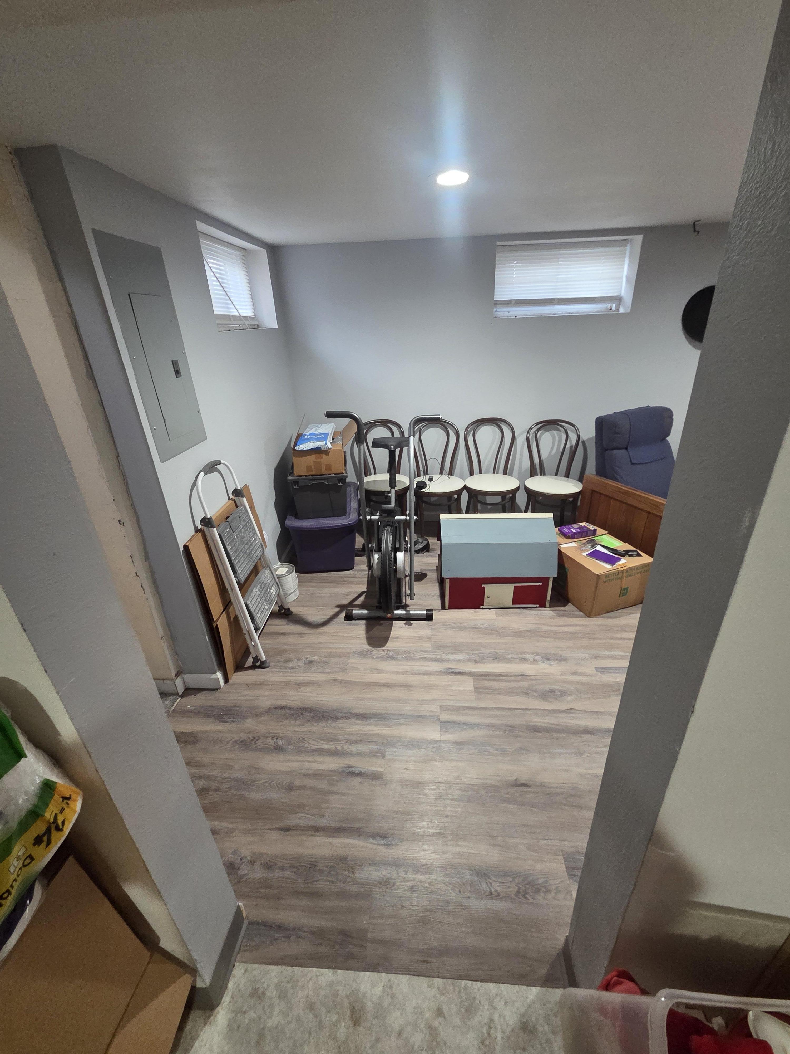 Restored basement family room with new laminate flooring, demonstrating the completed water damage and sewage remediation in a clean, organized space.