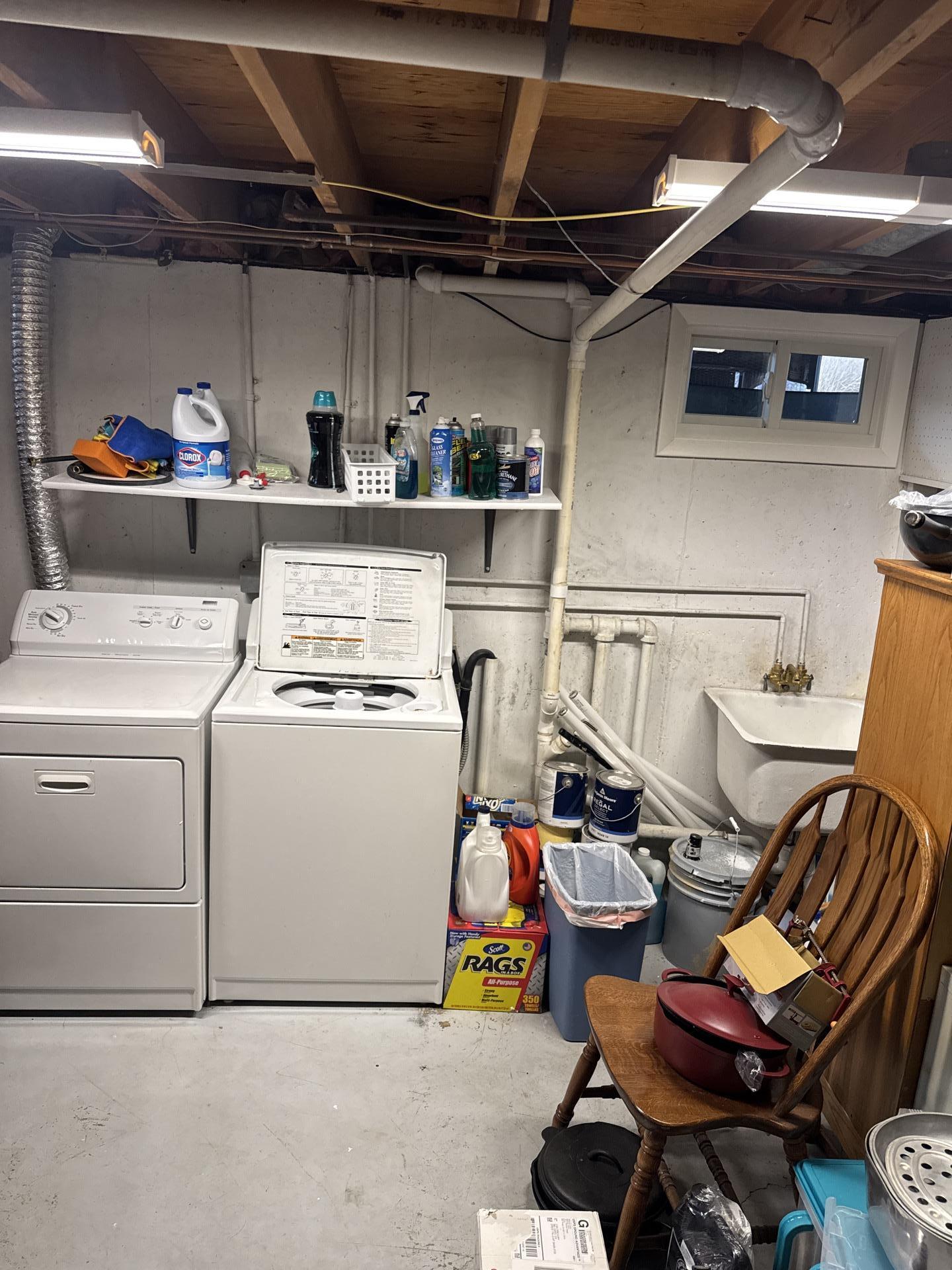 Basement laundry room with washing machine, dryer, shelves, and utility sink, typically an area prone to water damage