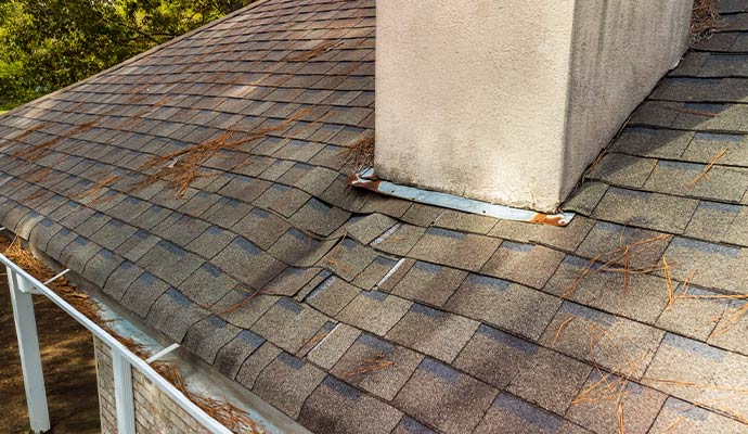 Damaged roof shingles near chimney