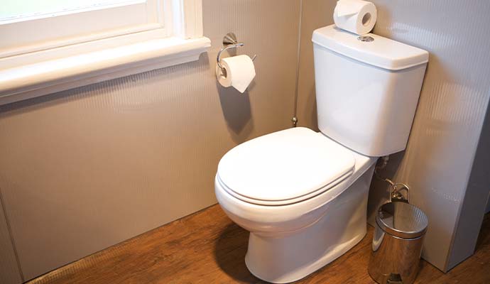 White toilet in a bathroom with wood flooring